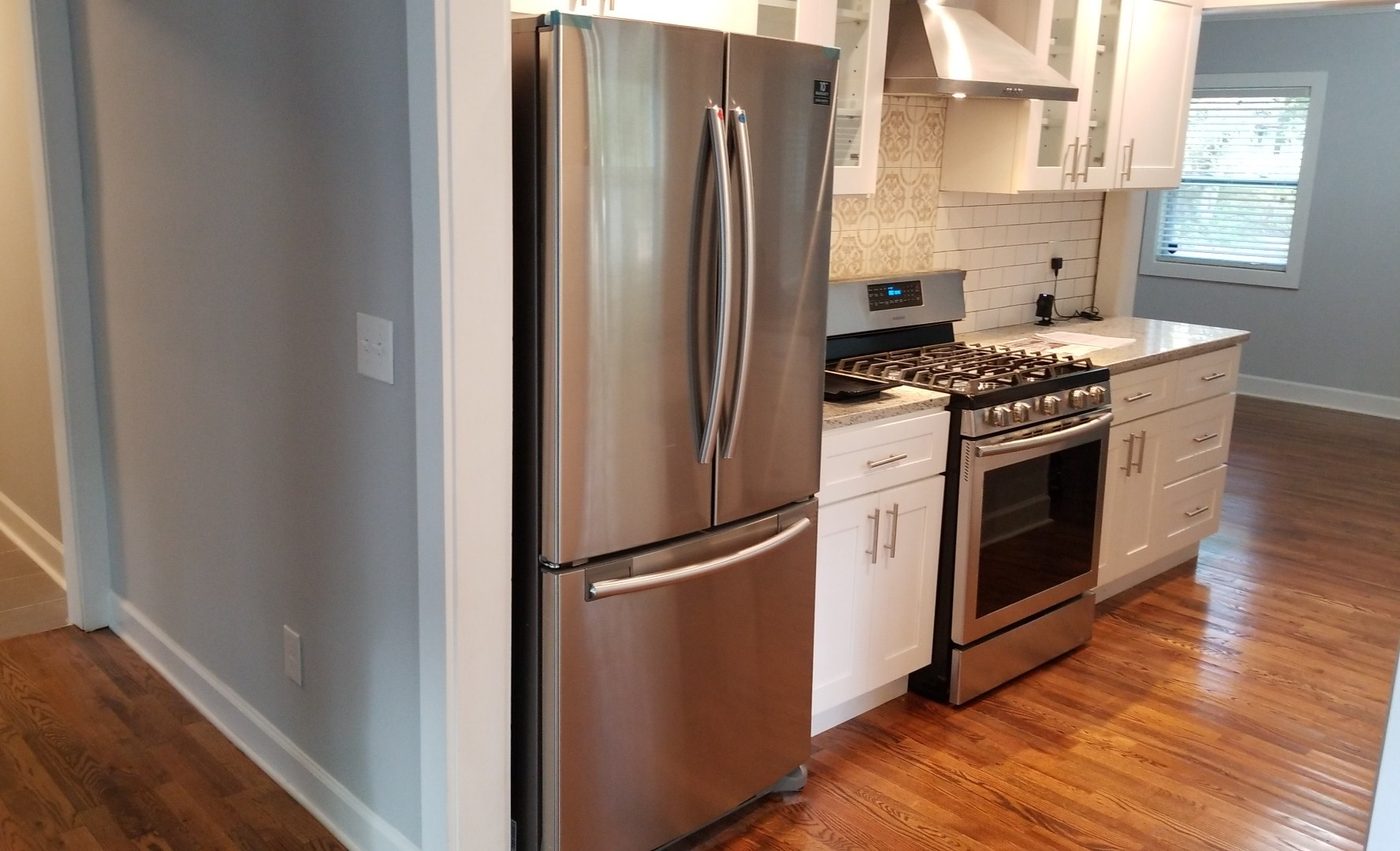 Fully renovated kitchen with new white cabinets, granite counters, subway-tile backsplash, and stainless appliances