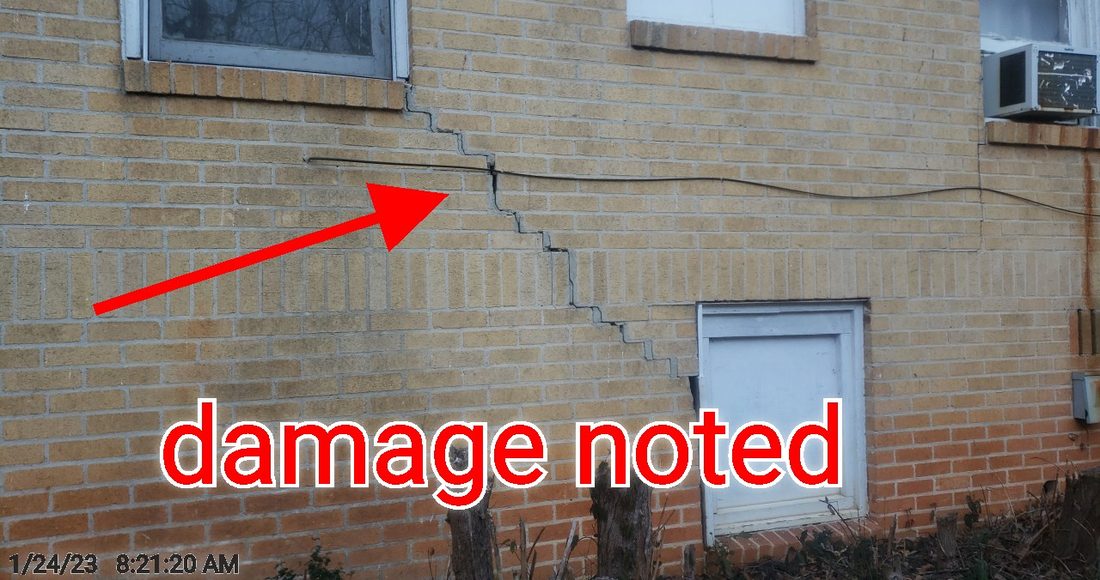 A stair-step settlement crack running through the exterior brick wall